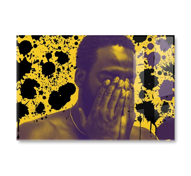black man holding his face in his hands against yellow background with black splatters